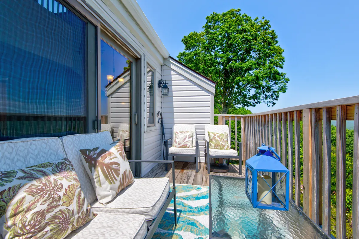 A welcoming exterior seating area with plush pillows and a blue lantern, ideal for lounging and enjoying the view. The vibe is tranquil and inviting, perfect for unwinding after exploring nearby towns or sharing a sunset together.