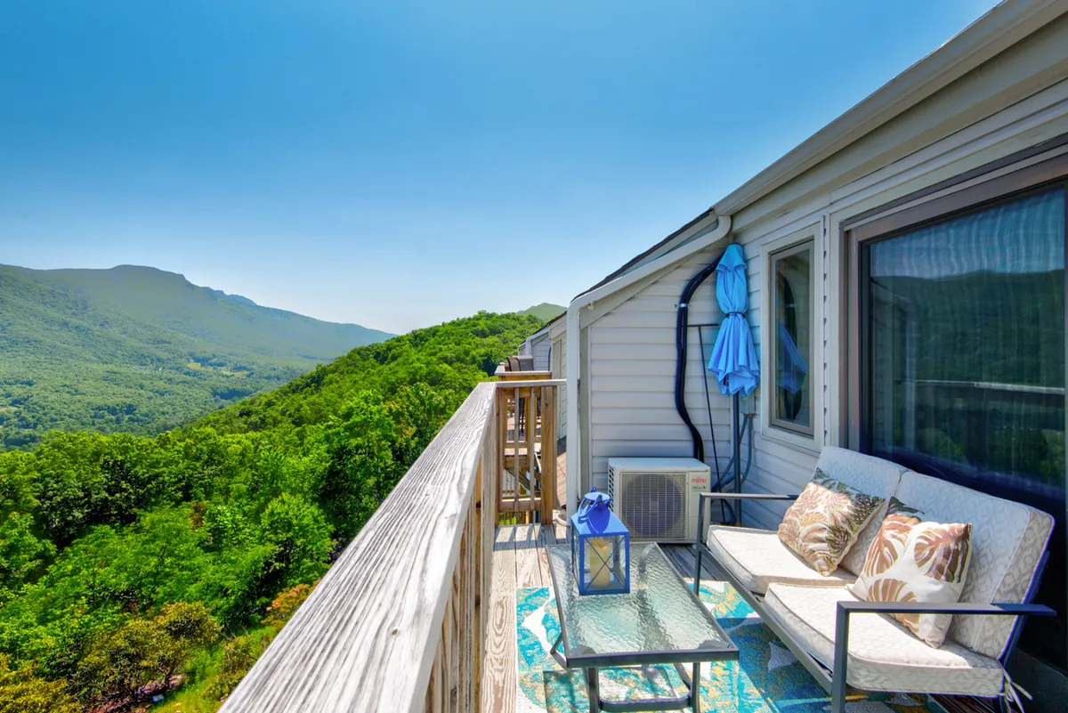 This exterior image features a private outdoor seating area adorned with decorative pillows and a lantern, set against the stunning backdrop of mountain views. A table is set up for enjoying beverages, and the scene is imbued with a peaceful, inviting mood, perfect for couples to relax and soak in sunrise or sunset together.