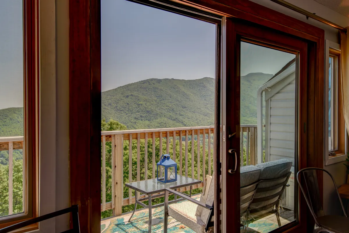 A private balcony with comfortable outdoor seating overlooks a picturesque mountain view. Decorative lanterns add a cozy touch, while the vantage point is perfect for taking in the snow-covered peaks or enjoying a warm drink after a winter adventure.