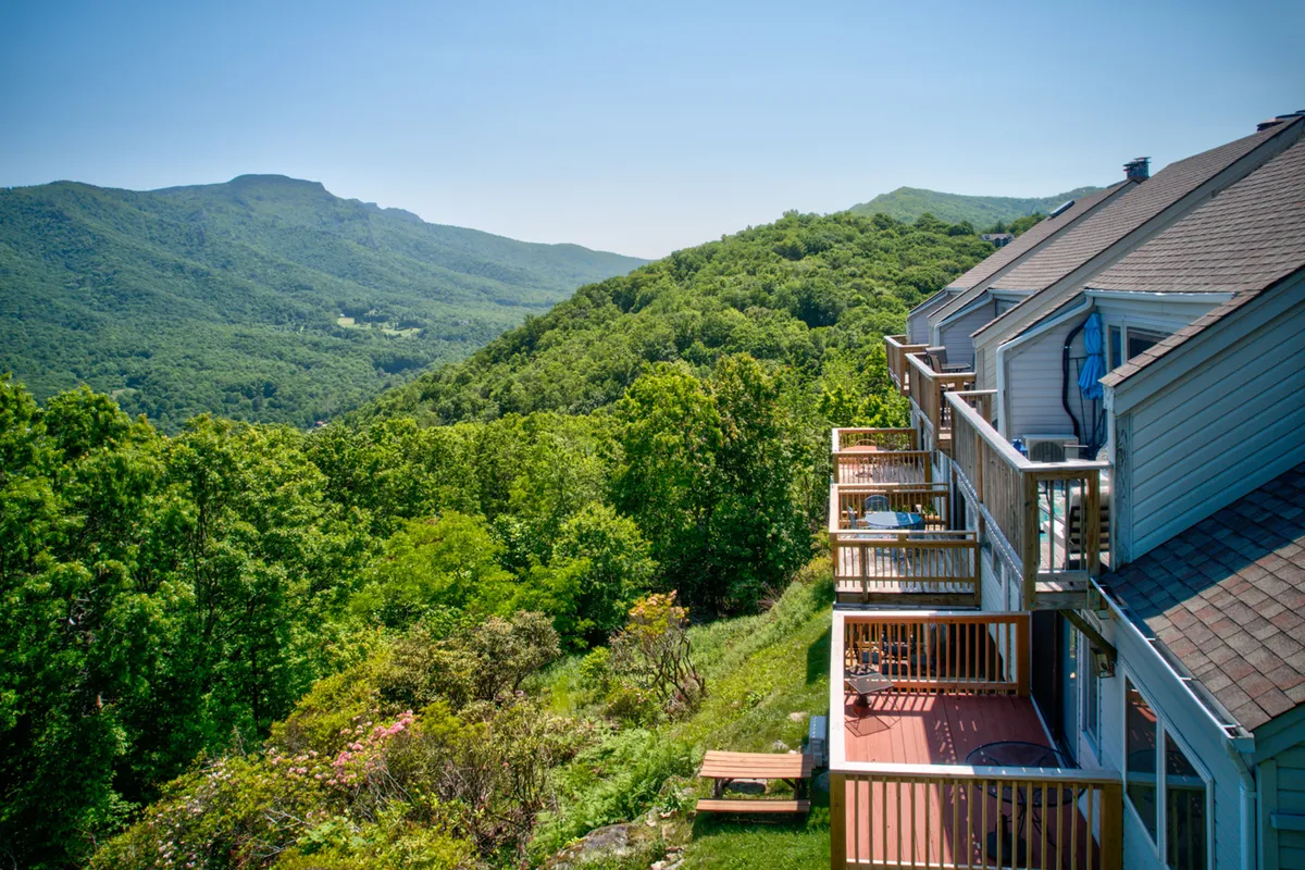 This exterior image features the balconies of a condo overlooking a breathtaking mountain view and lush greenery. The scene conveys peaceful outdoor living, with the balcony offering a place to relax and take in the natural surroundings.